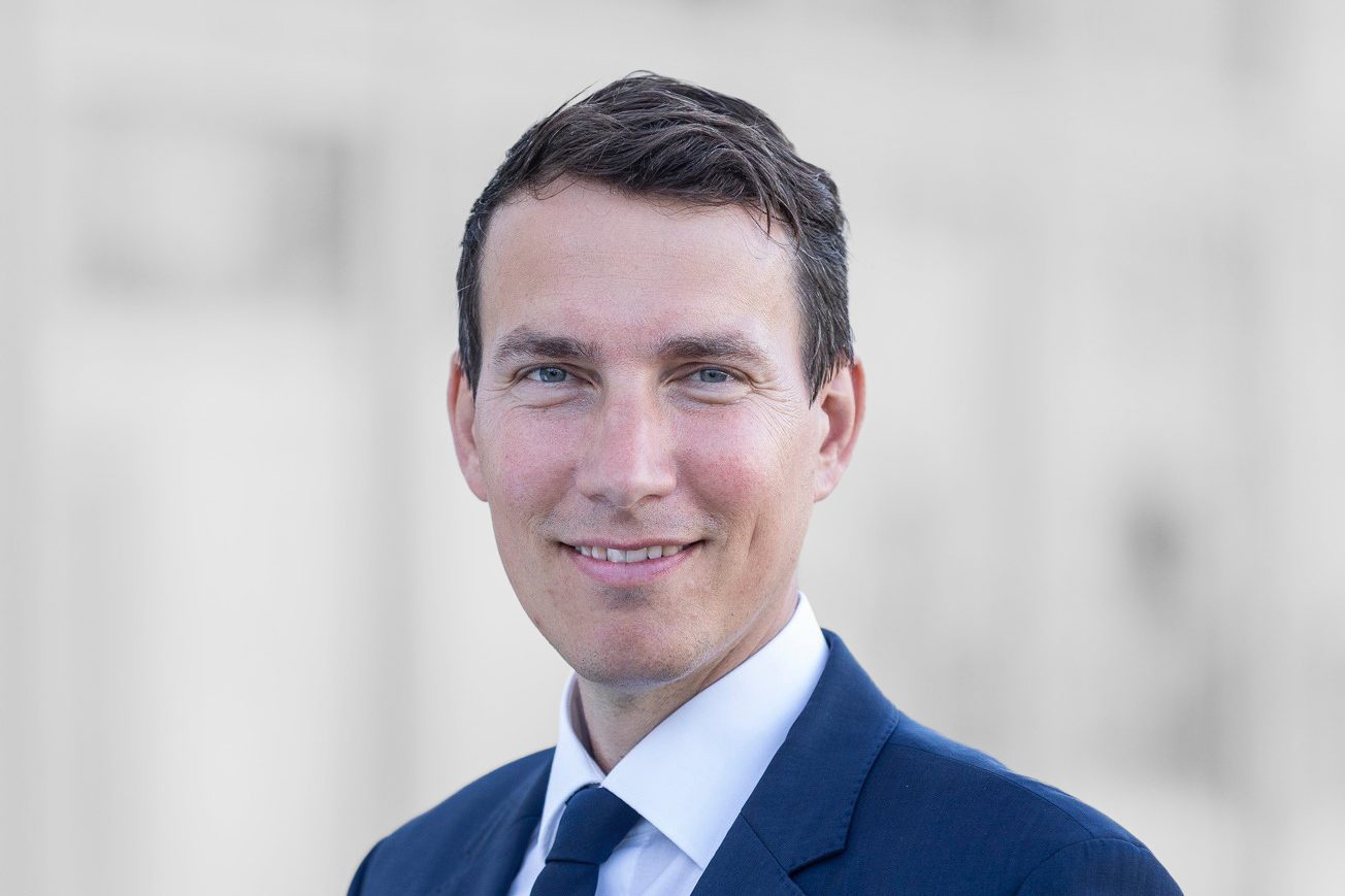 Eine Person in einem dunklen Anzug und einer blauen Krawatte.