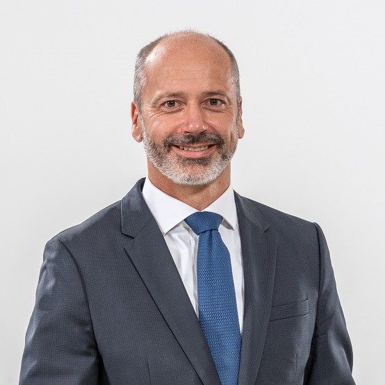 Die abgebildete Person trägt einen hellblauen Anzug mit einem weißem Hemd und einer blauen Krawatte.